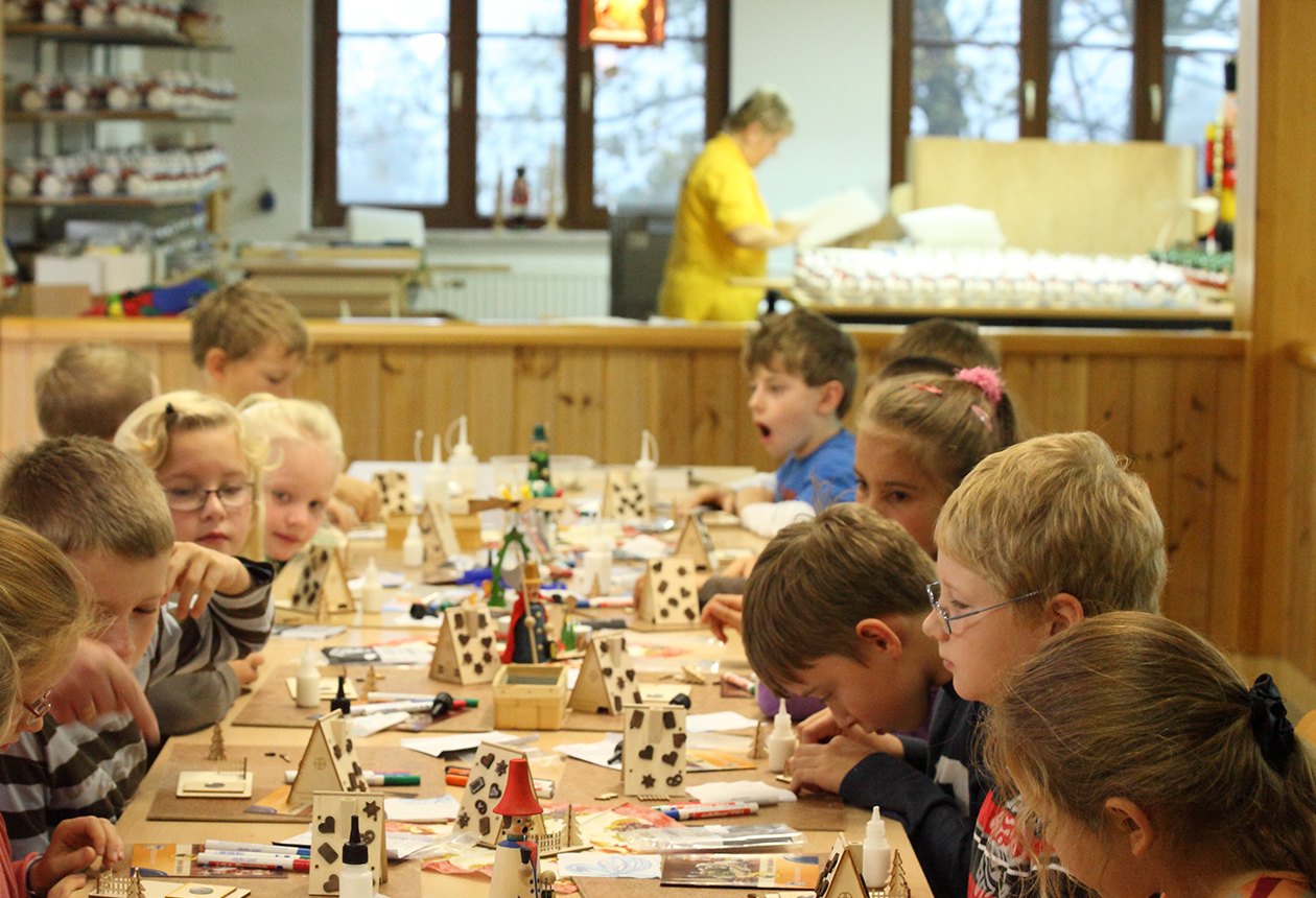 Kinder basteln an einem langen Tisch in unserer Bastelwerkstatt