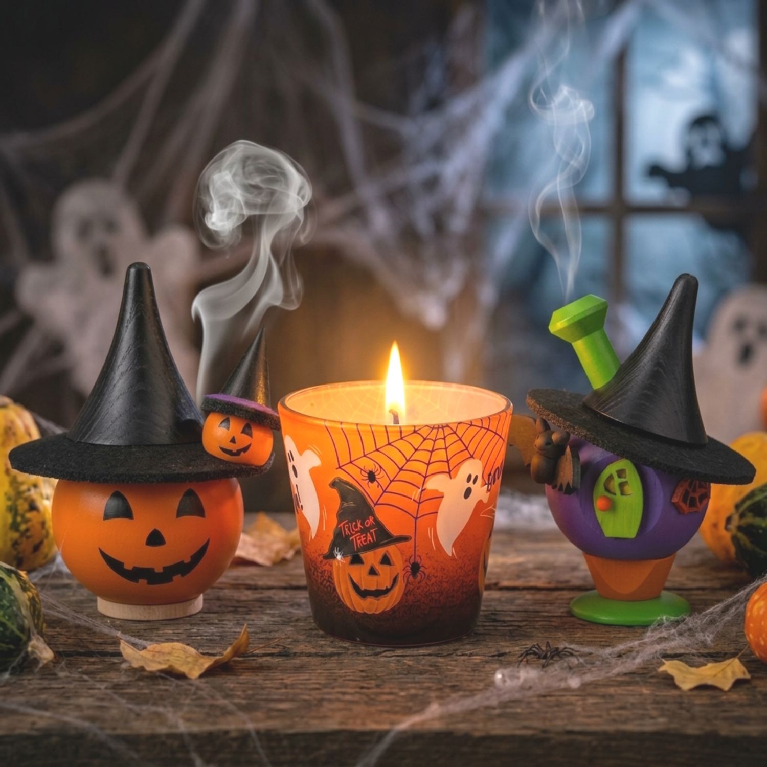 Räucherkürbis und Hexenhaus mit Halloween-Duftkerze zwischen Spinnweben und Kürbissen